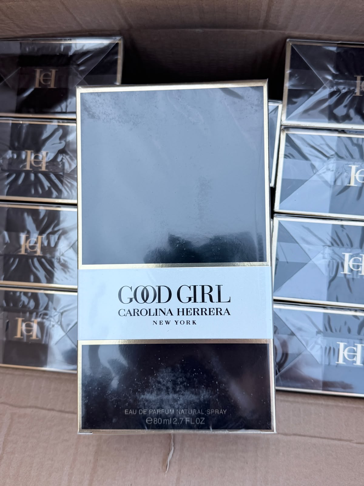A boxed fragrance product labeled GOOD GIRL Carolina Herrera New York, shown standing upright in a cardboard box with several matching boxes around it.