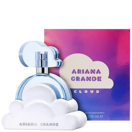 Ariana Grande Cloud perfume bottle and its colorful packaging box. The bottle is shaped like a white cloud with a light blue arch over it, and the box features a pink-to-purple gradient with a beige cloud graphic containing the text 'ARIANA GRANDE CLOUD'.