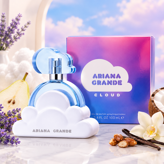 Ariana Grande Cloud perfume bottle and packaging box on a reflective white surface, styled with lavender, a pear, vanilla bean, and white flower against a sky-and-cloud backdrop.