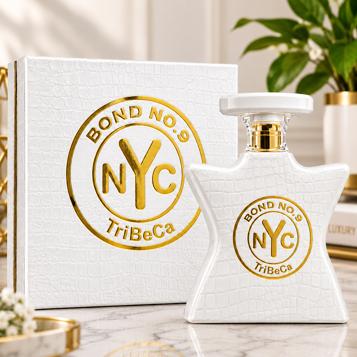 A white textured perfume bottle with a gold circular NYC Bond No. 9 TriBeCa logo stands in front of a matching white textured box on a marble surface.