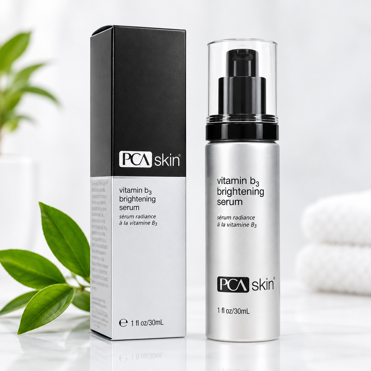 PCA skin Vitamin B3 Brightening Serum shown with its black and white retail box and the silver pump bottle with a clear cap, styled on a white surface with soft green leaves in the background.