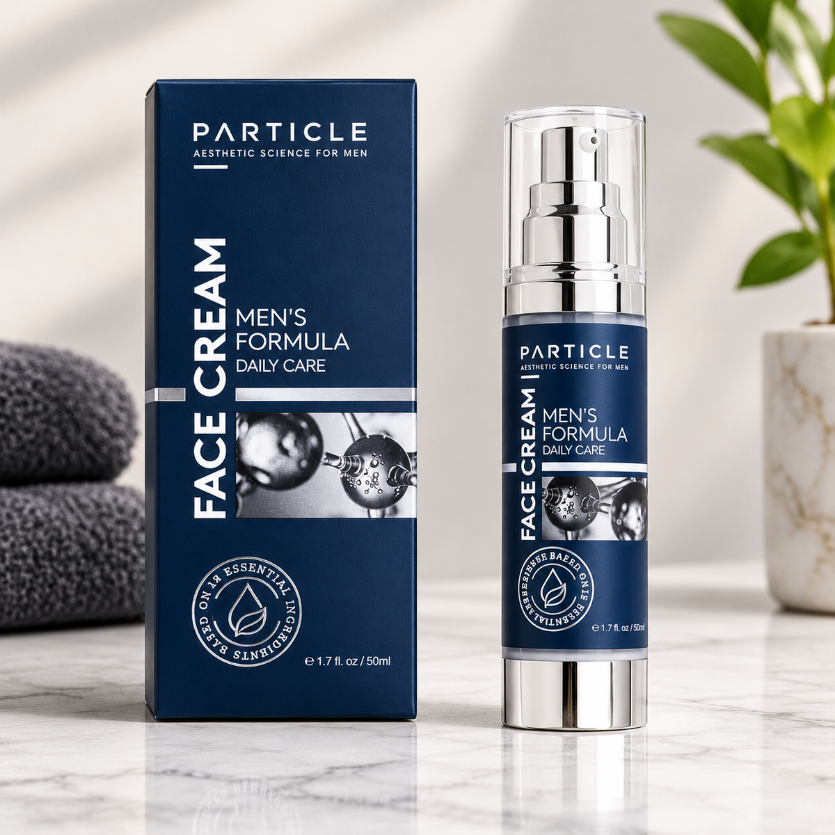 Particle Face Cream for Men shown as a navy blue box next to a matching pump bottle with a silver pump and base, set on a marble surface with folded towels and a plant in the background.