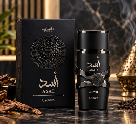 A black cylindrical perfume bottle with Arabic text and a circular emblem stands beside its matching black box on a dark marble surface. Decorative wood pieces, coffee beans, and a brass incense burner appear in the background, with a smoky effect around the bottle.
